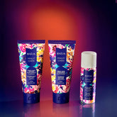 Trio de soins Minuit Chéri sur fond dégradé violet et orangé : crème corps velours adoucissante, crème exfoliante illuminatrice et mousse de douche hydratante.