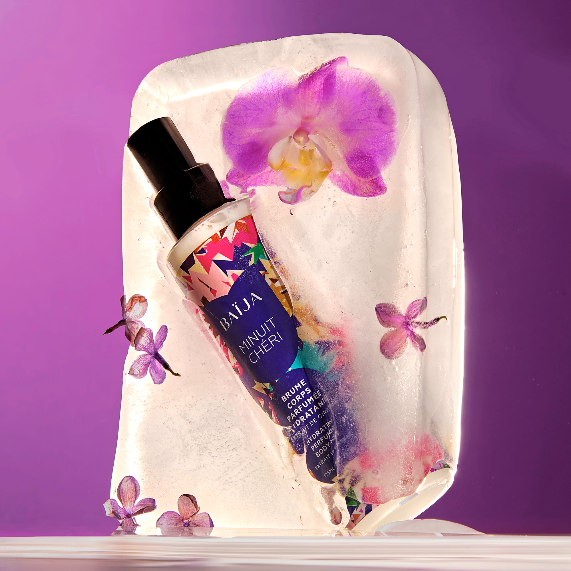 Brume corps parfumée hydratante Minuit Chéri emprisonnée dans un bloc de glace orné de fleurs violettes et d’orchidées, sur fond mauve, évoquant la fraîcheur envoûtante et la sensualité florale de la brume.