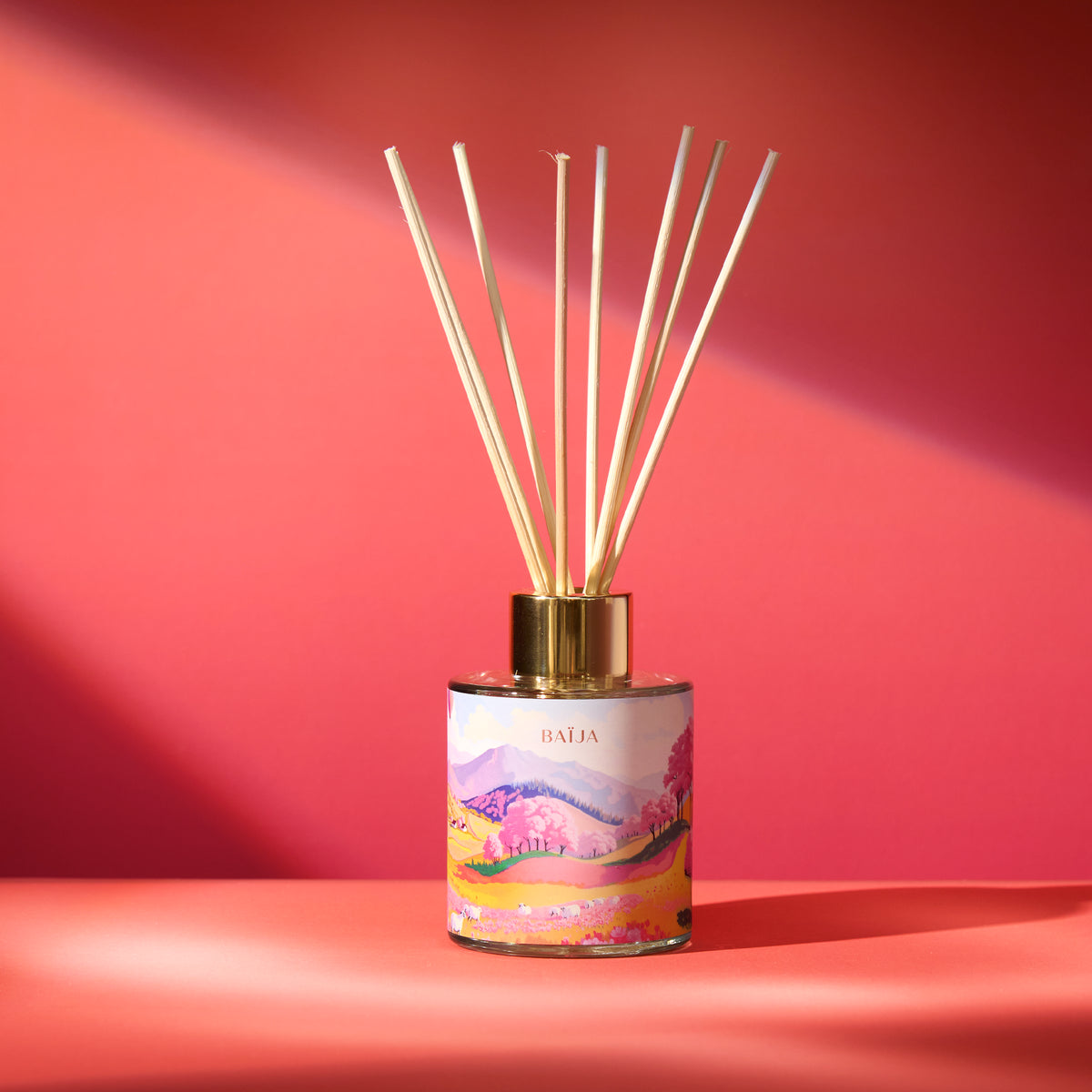 Diffuseur de parfum d’intérieur Sweet Sunday Baïja avec bâtonnets en rotin et décor illustré aux paysages printaniers.
