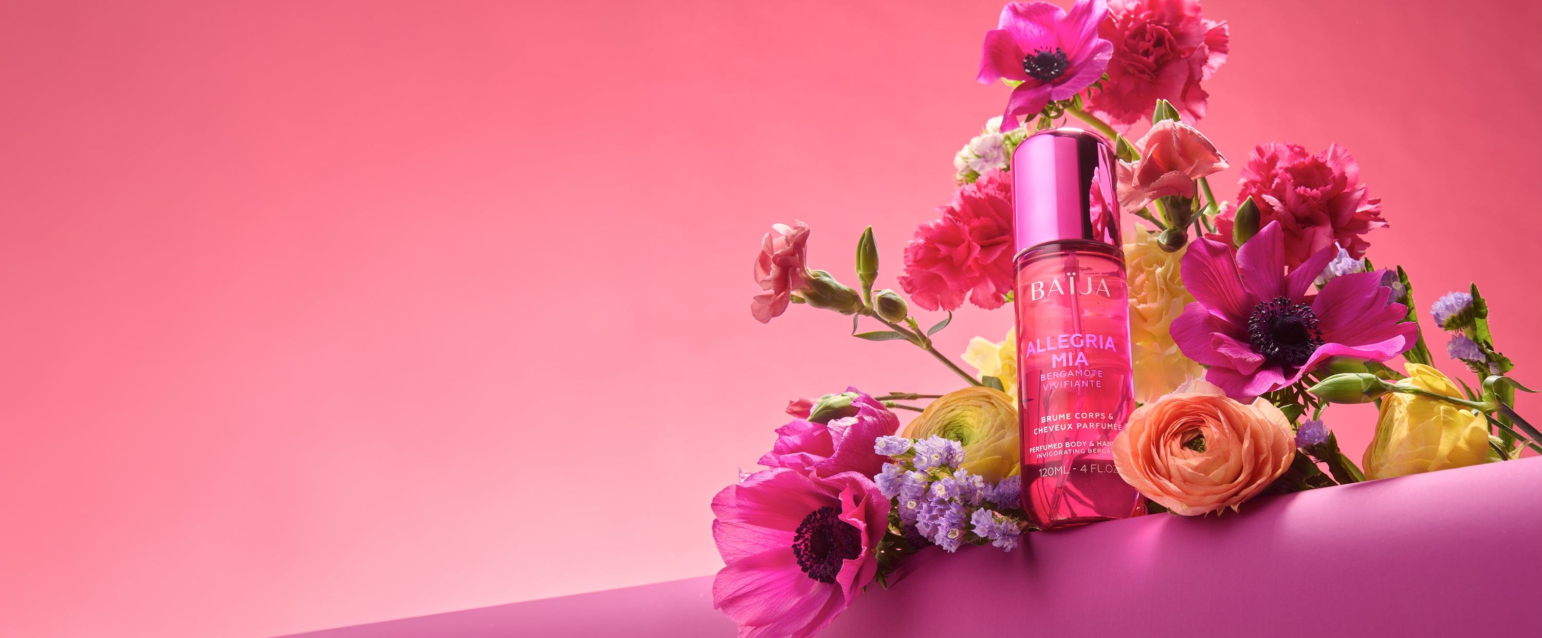 Bandeau panoramique : flacon Baïja Allegria Mia au centre d’un bouquet de fleurs vives, grand fond rose dégradé avec espace vide à gauche.