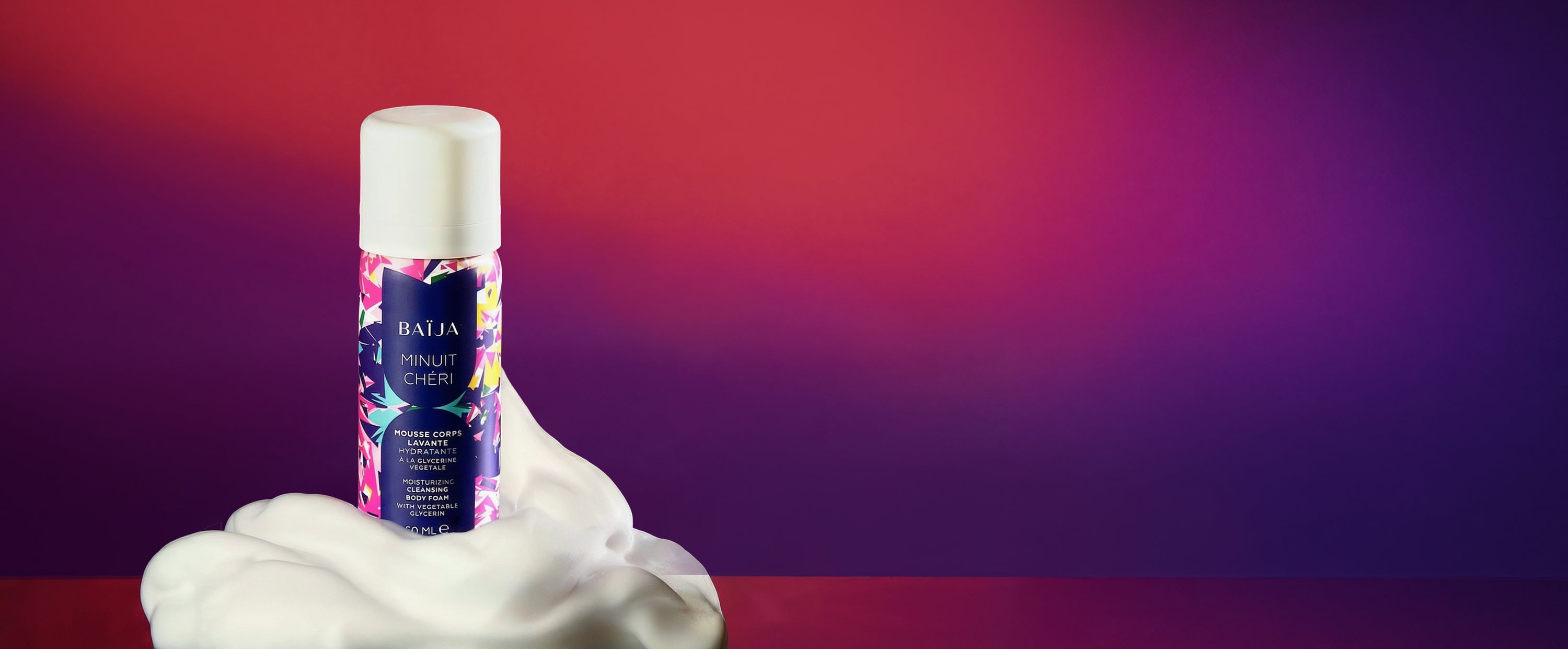Flacon de mousse corps lavante hydratante BAÏJA Minuit Chéri, capot blanc, entouré d’une mousse généreuse, sur un fond rouge et violet en dégradé.