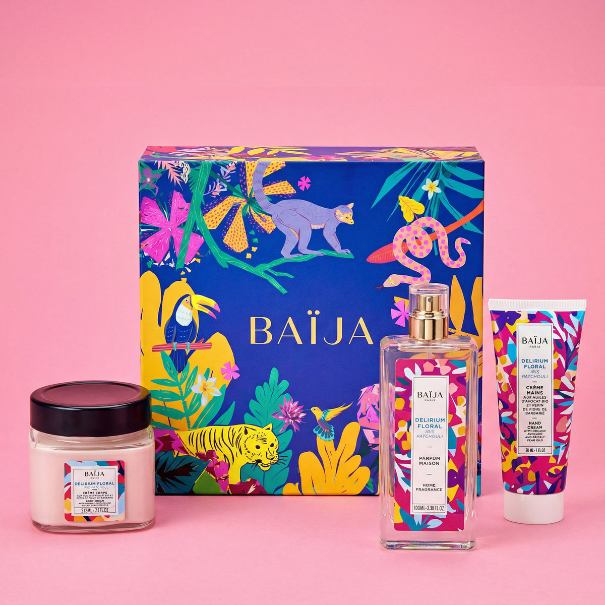 Coffret BAÏJA illustré façon jungle bleu, avec trois produits Delirium Floral iris patchouli : pot de crème corps, flacon de parfum maison et tube de crème mains, posés sur fond rose.