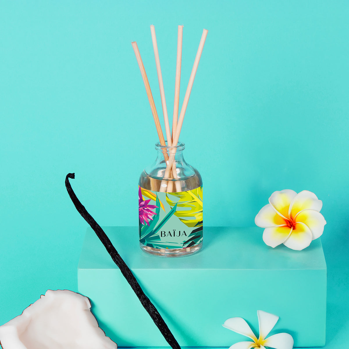 Bouquet parfumé BAÏJA Moana avec bâtonnets diffuseurs, entouré d’une gousse de vanille, d’un morceau de noix de coco et de fleurs de tiaré sur un fond turquoise lumineux.