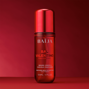 Packshot de la brume parfumée Baïja Bal Valentino freesia chic, flacon transparent rouge avec capot brillant, sur fond rouge.