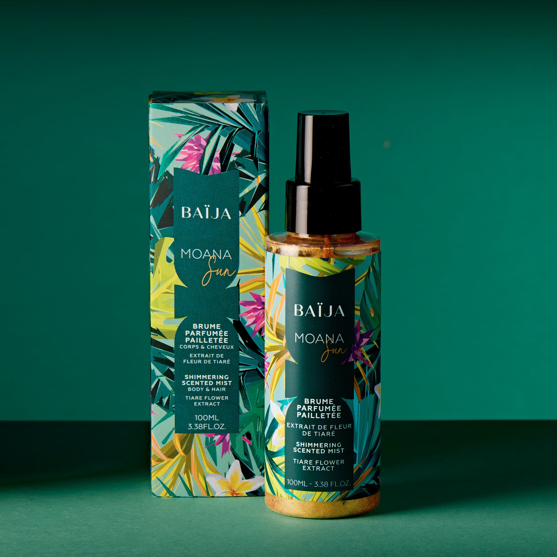 Photo en ambiance : le flacon pailleté et sa boîte sur un fond vert/bleu-vert, composition plus aérée qu’un packshot. Le flacon est au premier plan, la boîte légèrement en retrait. Les paillettes se distinguent dans le liquide. Ombres marquées, lumière chaude.