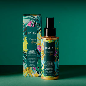 Photo en ambiance : le flacon pailleté et sa boîte sur un fond vert/bleu-vert, composition plus aérée qu’un packshot. Le flacon est au premier plan, la boîte légèrement en retrait. Les paillettes se distinguent dans le liquide. Ombres marquées, lumière chaude.