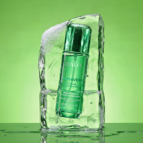 Flacon vert Baïja Primavera brume parfumée corps et cheveux, encastré dans un bloc de glace translucide avec gouttes d’eau, sur fond vert lumineux.