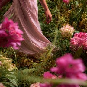 Plan en mouvement : robe rose vaporeuse au milieu d’un parterre de fleurs roses, verts et jaunes, rendu très immersif.