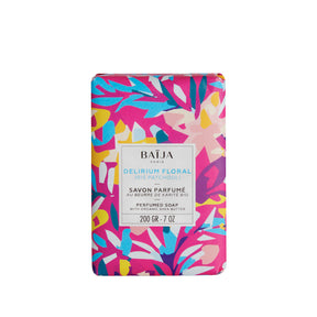 Pain de savon parfumé BAÏJA “Delirium Floral” iris patchouli, enrichi en beurre de karité bio, emballé dans un papier graphique rose, bleu et jaune, photo sur fond blanc.