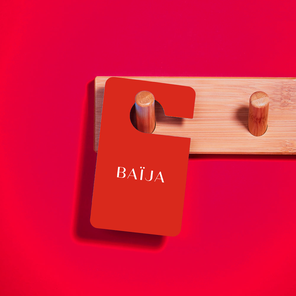 Parfum voiture Bal Valentino suspendu sur fond rouge. 