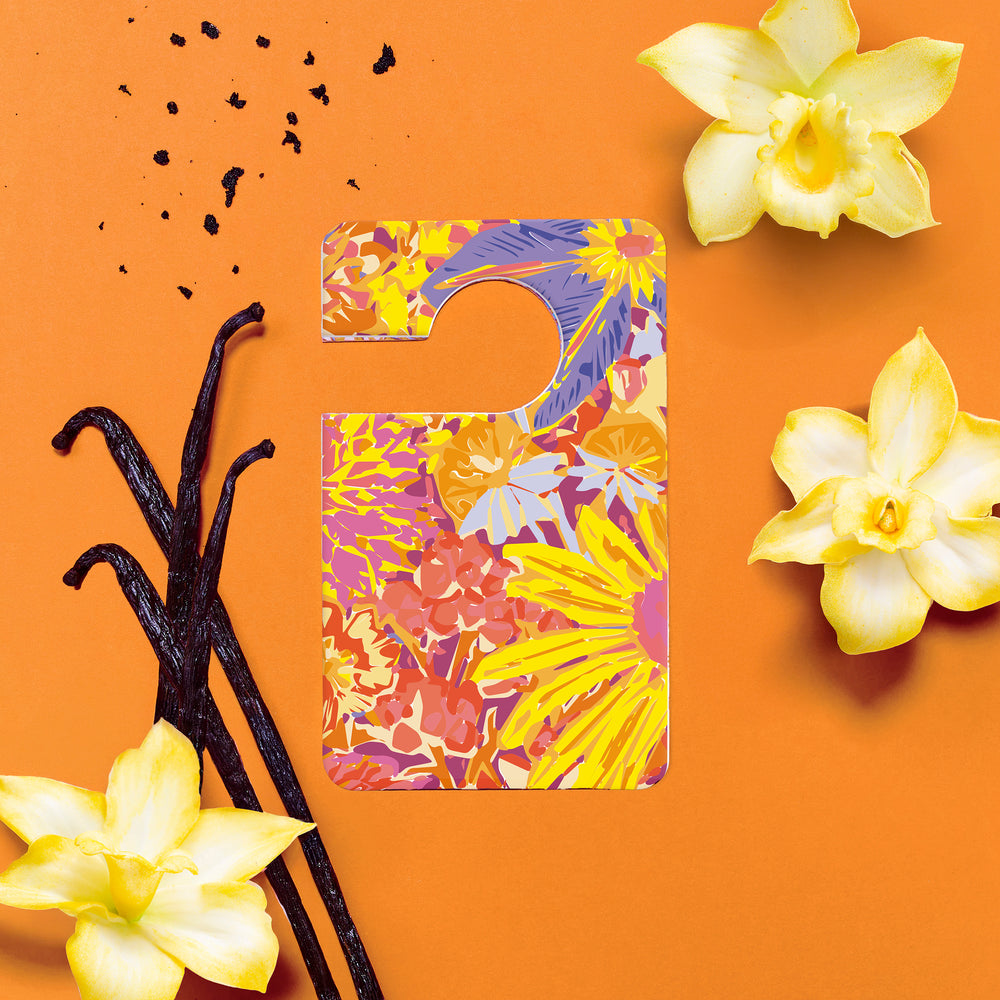 Parfum voiture Indian Sunset entouré de fleurs de vanille et gousses sur fond orange. 