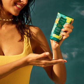 Fluide solaire SPF50+ Baïja Moana Sun versé dans la main, texture fondante et protection UVA UVB pour visage et corps en lumière solaire