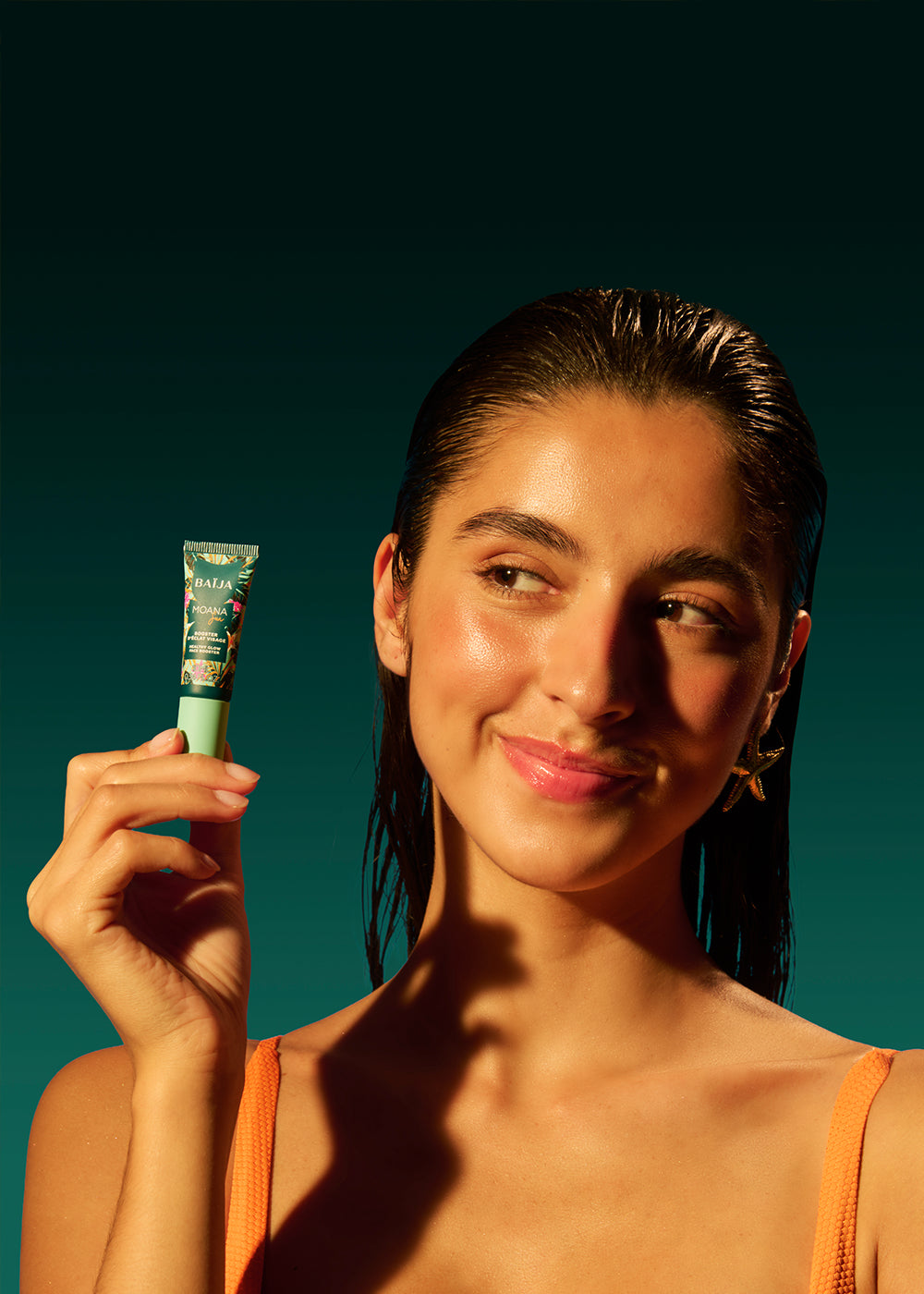 Gros plan sur le booster éclat visage Moana Baïja présenté par une femme au teint lumineux, dans un univers inspiré des vacances et du soleil.