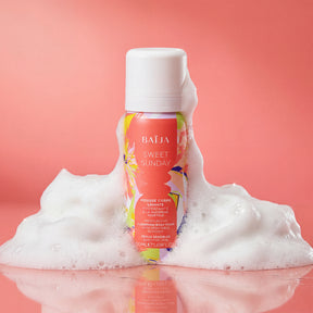 Mousse corps lavante hydratante Baïja Sweet Sunday à la glycérine végétale pour peaux sensibles, entourée d’une mousse onctueuse sur fond rose, évoquant un rituel de douche doux et réconfortant.