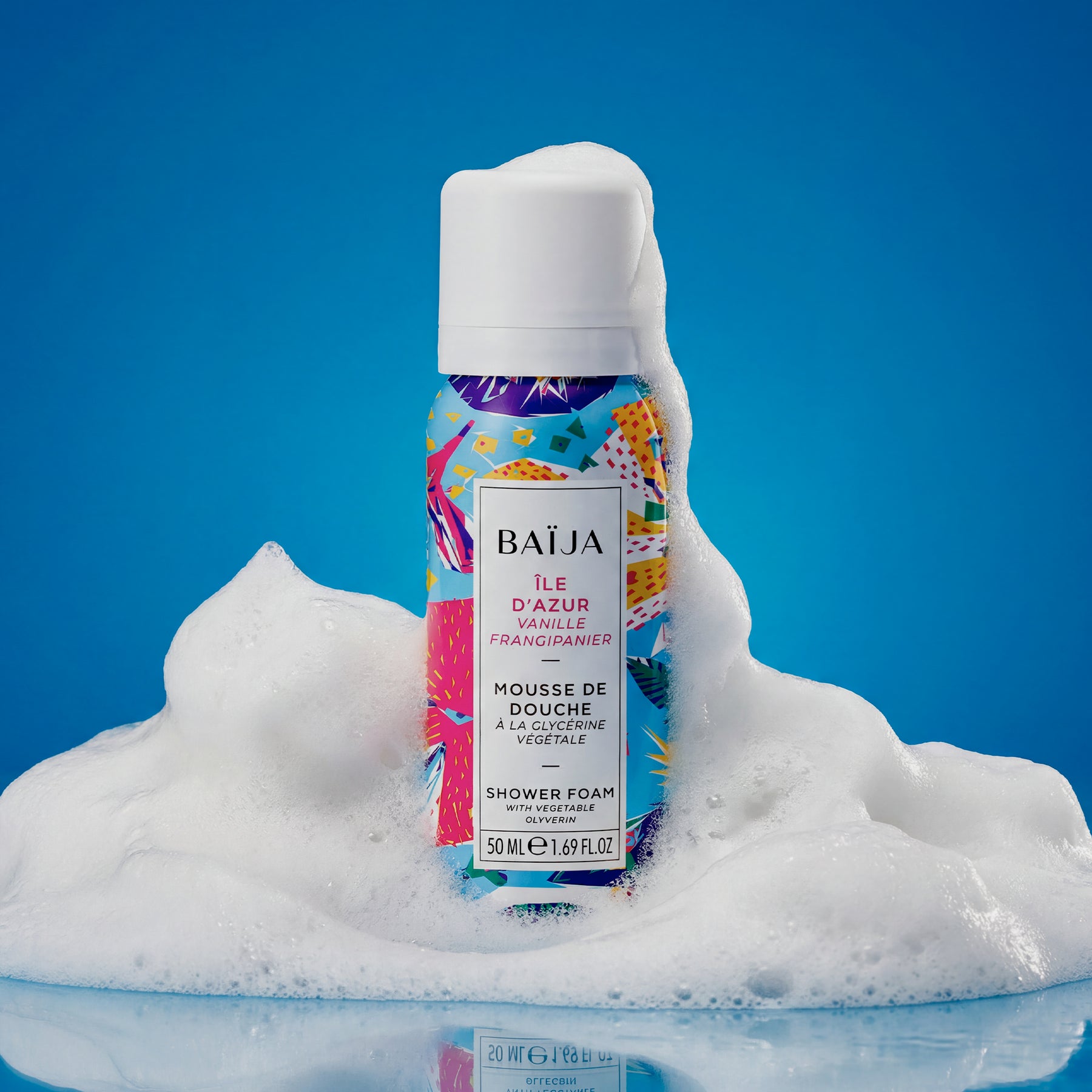 Mousse de douche Baïja Île d’Azur à la vanille et au frangipanier, enveloppée d’une mousse aérienne sur fond bleu, évoquant un moment de fraîcheur et de douceur.