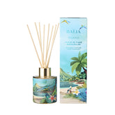 Bouquet parfumé Moana de Baïja, à la senteur de fleur de tiaré ensoleillée. Ce diffuseur de parfum d'intérieur se présente dans un flacon en verre cylindrique décoré d'un paysage tropical aux nuances turquoise et vertes, avec un col doré et des bâtonnets diffuseurs en bois naturel. À ses côtés, un coffret bleu turquoise illustré d'une plage paradisiaque, de palmiers, d'oiseaux exotiques et de fleurs tropicales. L'ensemble est photographié de face sur fond blanc.