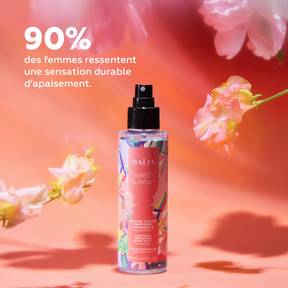 Brume parfumée apaisante Sweet Sunday entourée de fleurs pastel, illustrant une sensation durable de confort et de bien-être
