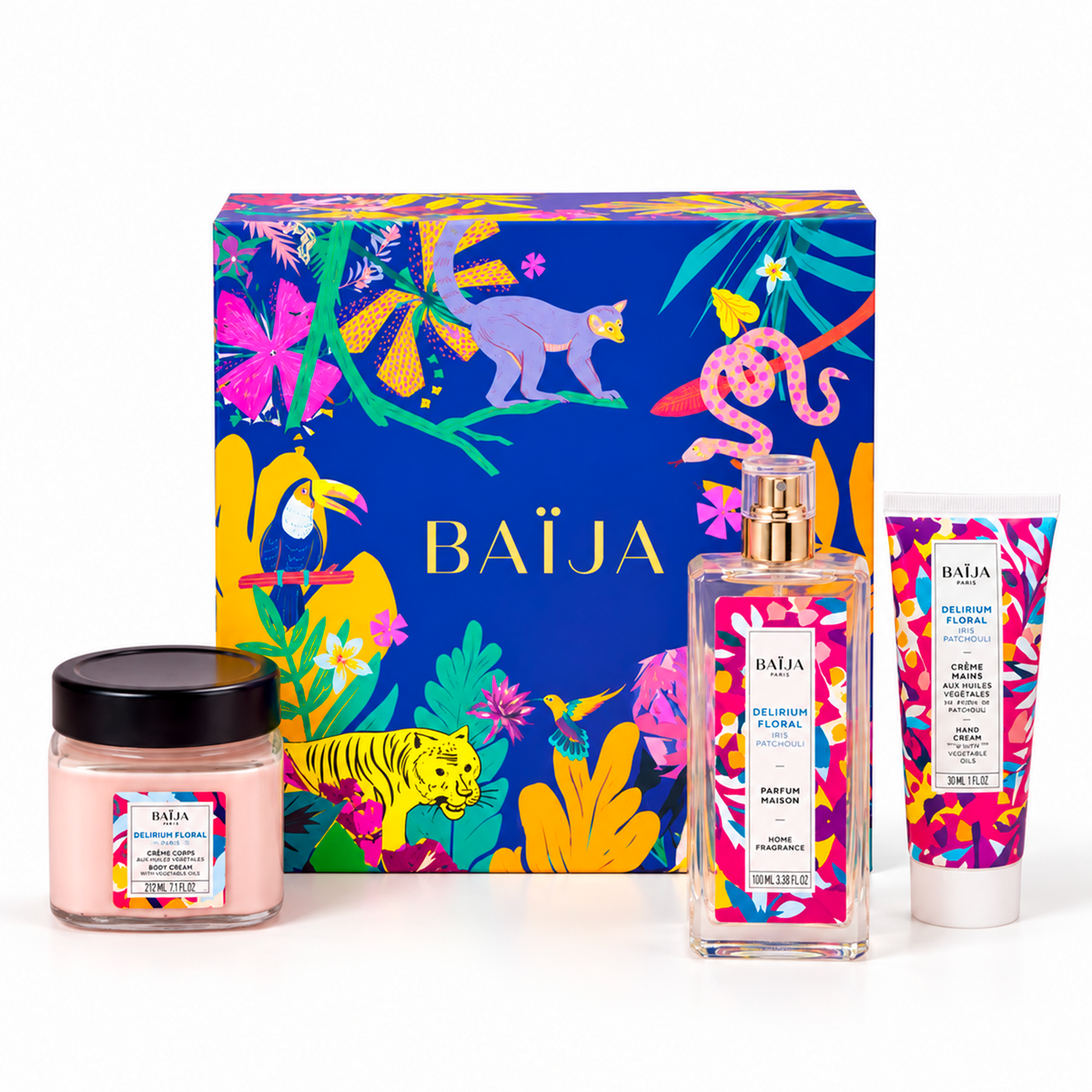 Packshot du coffret cadeau Délirium Floral de Baïja, composé d'un parfum maison Iris Patchouli de 100 ml, d'une crème mains aux huiles végétales de 30 ml et d'une bougie parfumée de 212 ml. Les trois produits sont présentés devant un coffret bleu roi aux illustrations tropicales multicolores, avec fleurs exotiques et animaux sauvages, sur fond blanc.