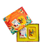 Packshot du coffret cadeau Vertige Solaire de Baïja, composé d'un savon solide parfumé de 200 g à la bergamote et à la tubéreuse, enrichi au beurre de karité bio, et d'un porte-savon en céramique jaune vif orné d'un papillon multicolore. Les deux produits sont présentés dans un coffret ouvert à intérieur jaune lumineux, accompagné de son couvercle orange vif décoré de fleurs tropicales, de feuillages exotiques et de papillons, sur fond blanc.