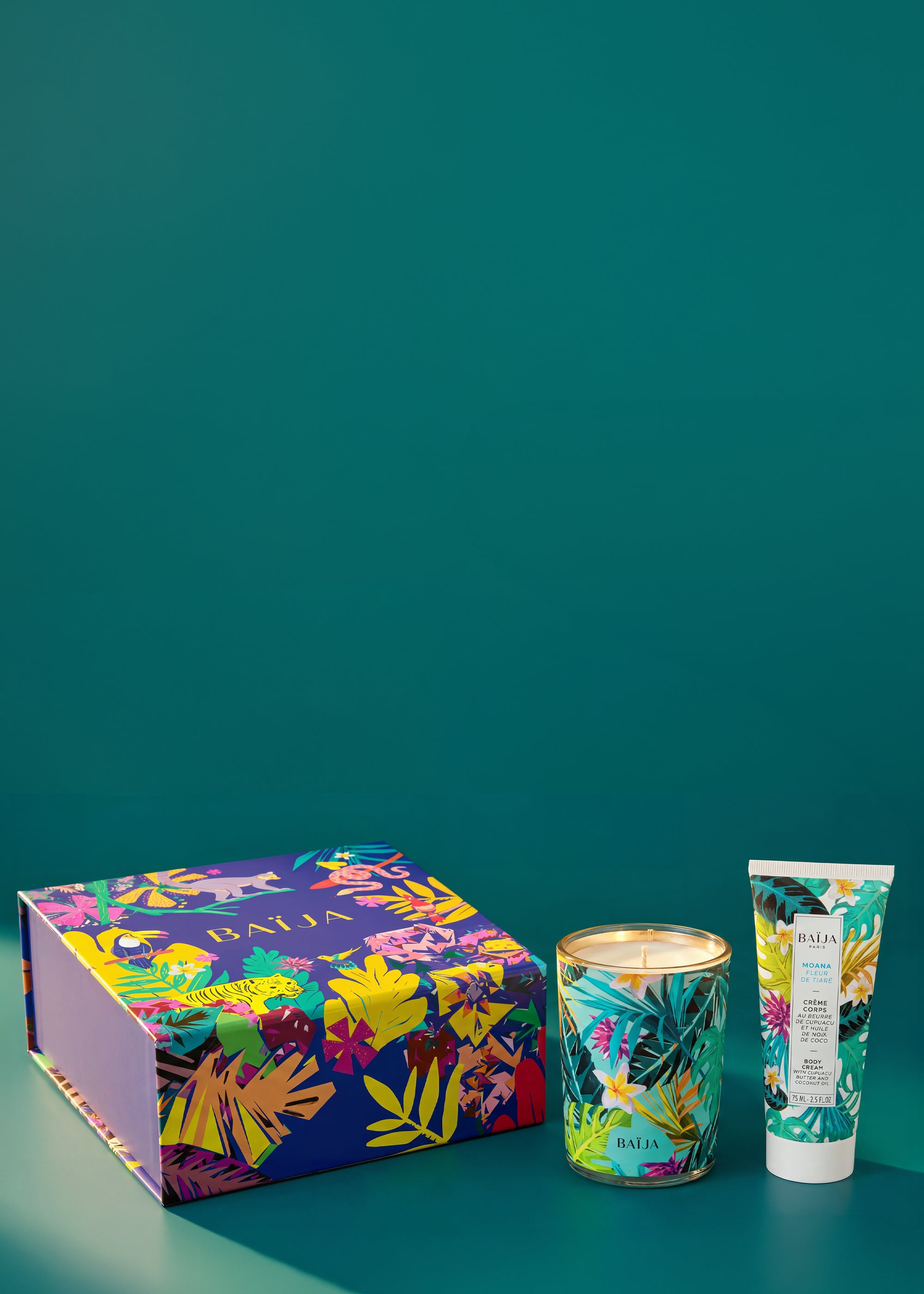 Coffret cadeau Baïja Moana fleur de tiaré accompagné d’une bougie parfumée et d’une crème corps nourrissante sur fond vert intense