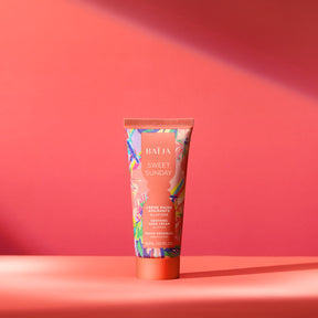 Tube de crème mains Sweet Sunday Baïja présenté dans une ambiance solaire aux nuances corail et rose