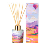 Packshot du diffuseur de parfum d’intérieur Sweet Sunday Baïja avec bâtonnets et coffret décoré d’un paysage pastel.