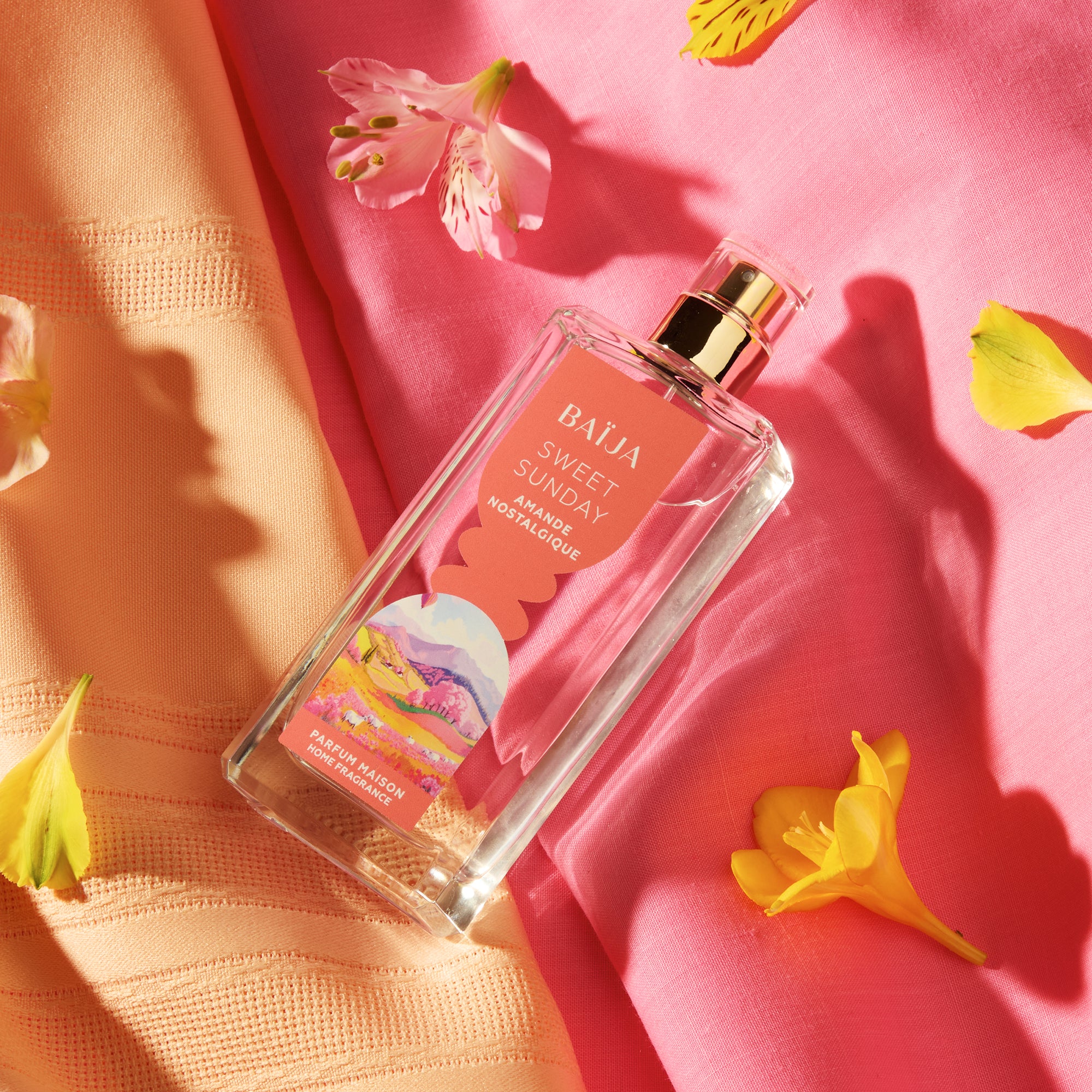 Flacon de parfum d’intérieur Sweet Sunday entouré de pétales et textiles aux tons rosés, ambiance florale délicate