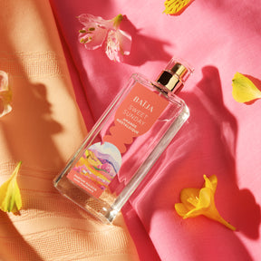 Flacon de parfum d’intérieur Sweet Sunday entouré de pétales et textiles aux tons rosés, ambiance florale délicate