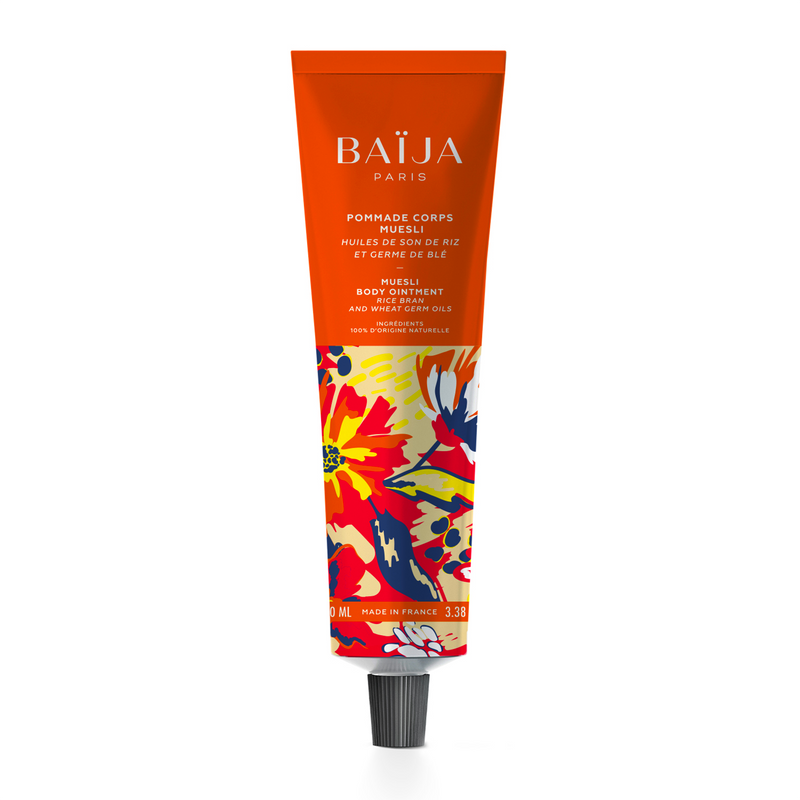 Pommade pour le corps Muesli de Baïja, formulée avec des ingrédients 100 % d'origine naturelle, aux huiles de son de riz et de germe de blé. Présentée dans un tube souple de 100 ml, orange vif sur la partie supérieure, avec un bouchon noir à visser. La partie inférieure est ornée d'illustrations florales et végétales aux couleurs éclatantes : rouge, jaune, bleu marine et orange. Le produit est photographié de face sur fond blanc.