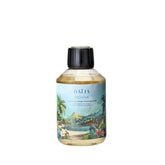 Recharge pour bouquet parfumé Moana de Baïja, à la senteur de fleur de tiaré ensoleillée. Cette recharge de parfum d'intérieur se présente dans un flacon transparent contenant un liquide légèrement doré, fermé par un bouchon noir strié. Son étiquette bleu turquoise illustre un paysage tropical avec une plage, des palmiers, des fleurs exotiques et une montagne en arrière-plan. Le produit est photographié de face sur fond blanc.
