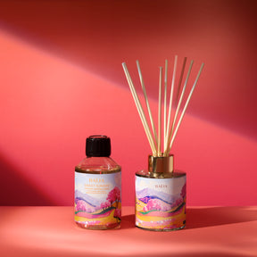 Recharge de parfum d’intérieur et diffuseur Sweet Sunday Baïja présentés sur fond rose aux accents printaniers.