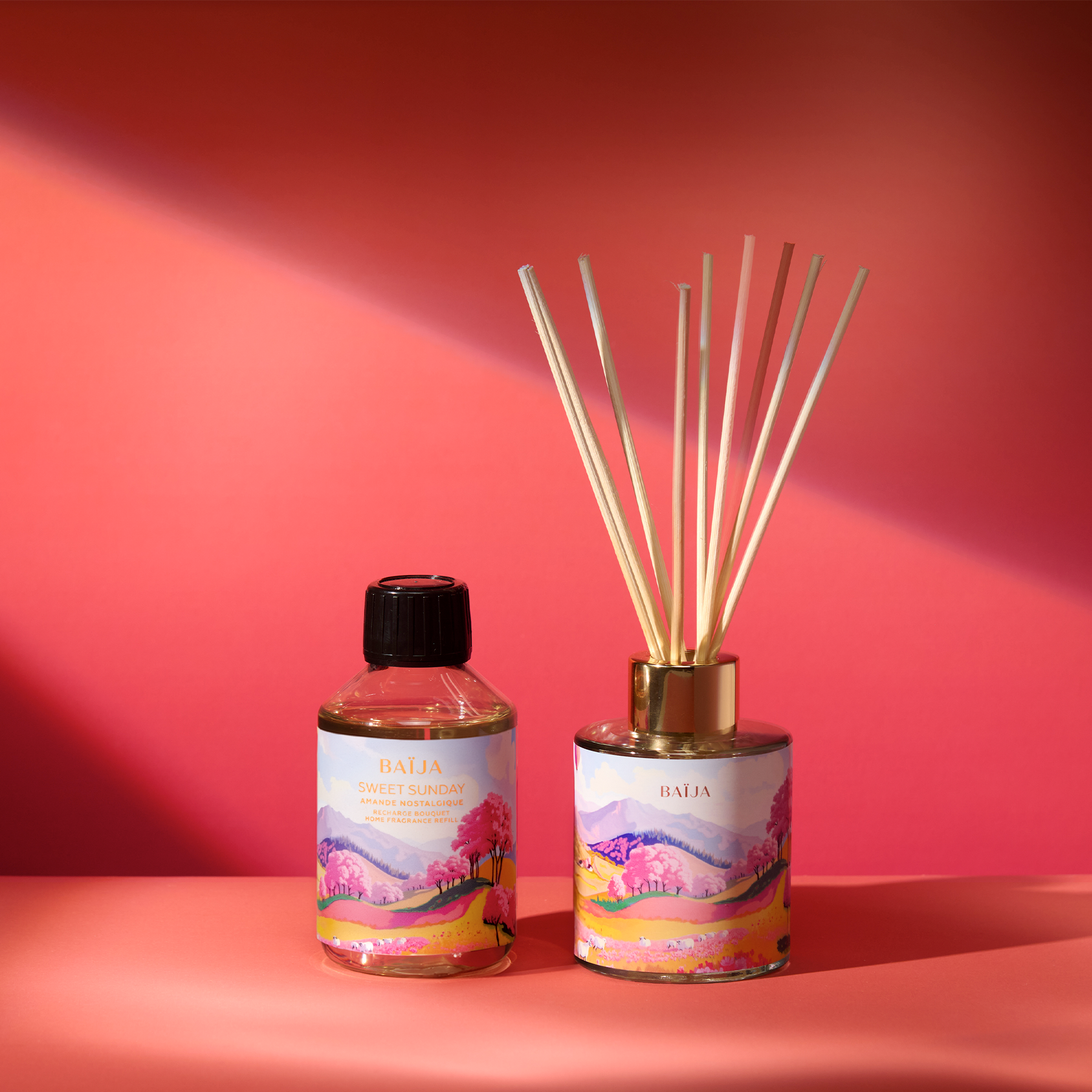 Recharge de parfum d’intérieur Sweet Sunday présentée aux côtés d’un diffuseur à bâtonnets, décor inspiré des paysages fleuris