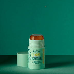 Photo produit/packshot d’un stick solaire “BAÏJA” vert menthe, présenté verticalement, bouchon ambré translucide visible (ou partiellement visible selon le cadrage). Fond clair/uni, rendu très net type e-commerce.