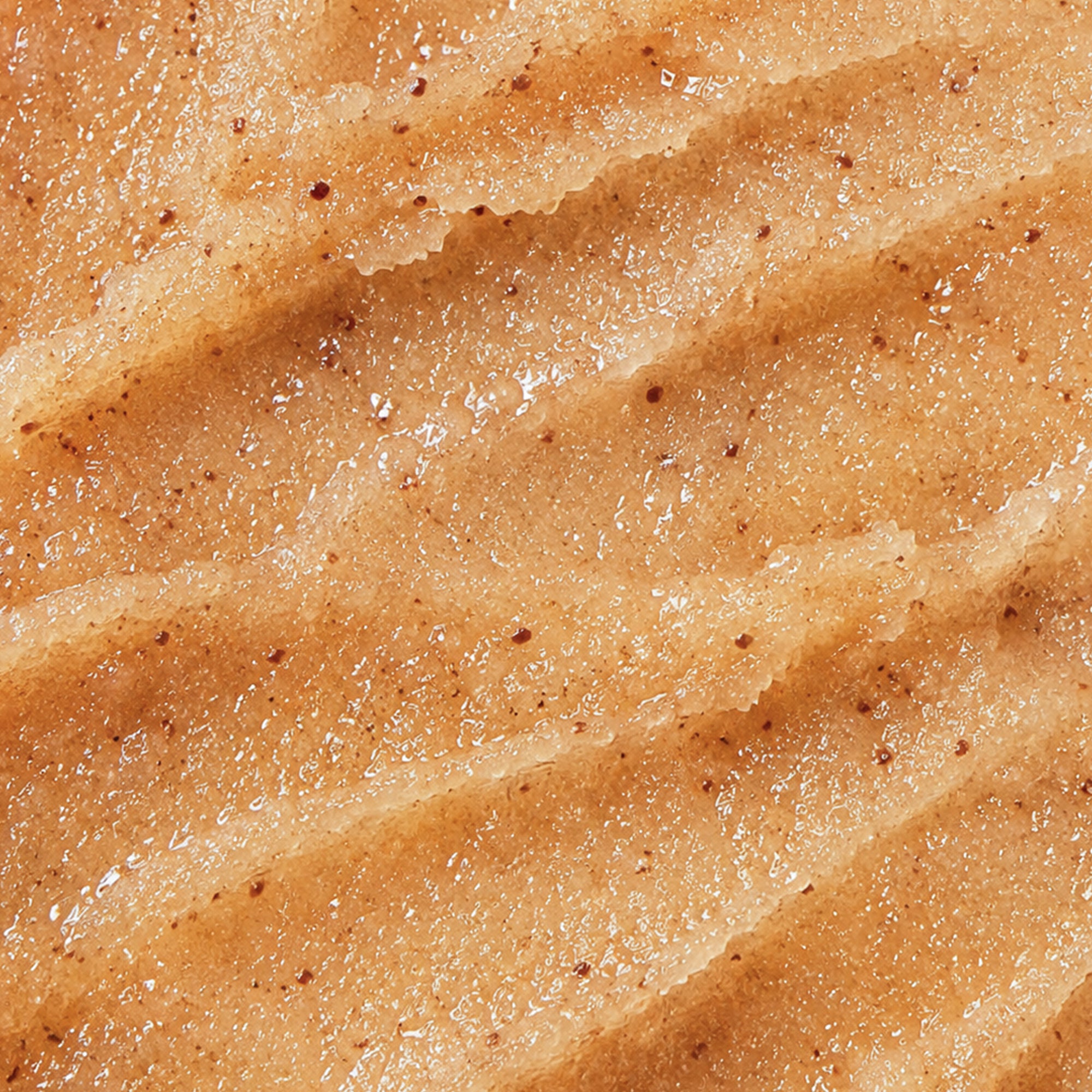 Gros plan sur la texture du gommage corps Sweet Sunday, riche en grains exfoliants et huile d’amande douce.